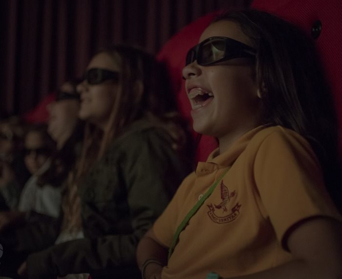 Familia disfrutando una película en 3D con anteojos especiales en una sala Multiplex